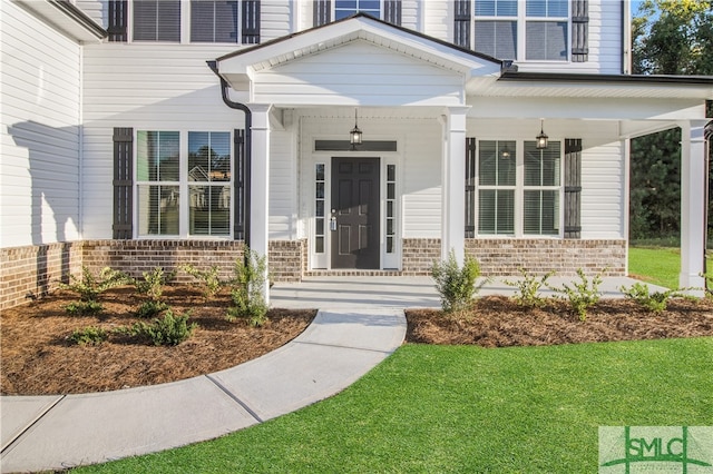 property entrance with a lawn and covered porch