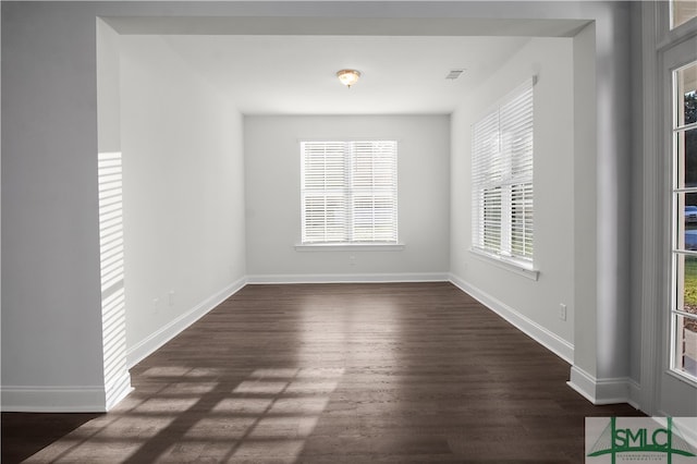 spare room featuring plenty of natural light and dark hardwood / wood-style flooring