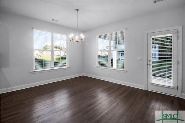 empty room featuring dark wood-type flooring and a chandelier