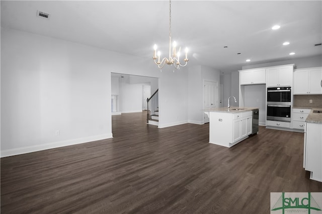 kitchen with hanging light fixtures, an island with sink, dark hardwood / wood-style flooring, stainless steel double oven, and sink