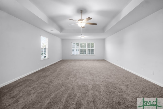 carpeted empty room featuring ceiling fan and a raised ceiling