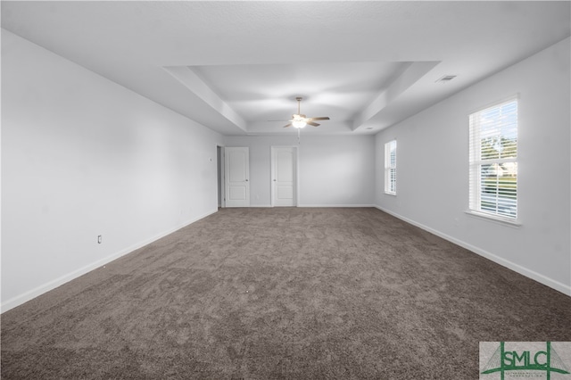 spare room with ceiling fan, a raised ceiling, and carpet flooring