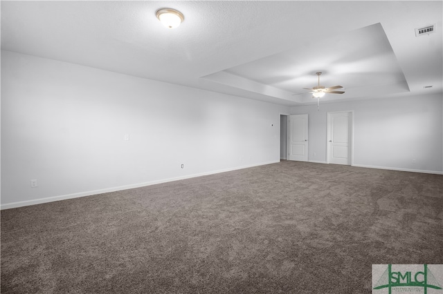 carpeted empty room with ceiling fan and a raised ceiling