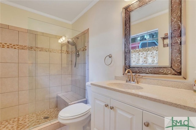 bathroom featuring vanity, toilet, ornamental molding, and tiled shower