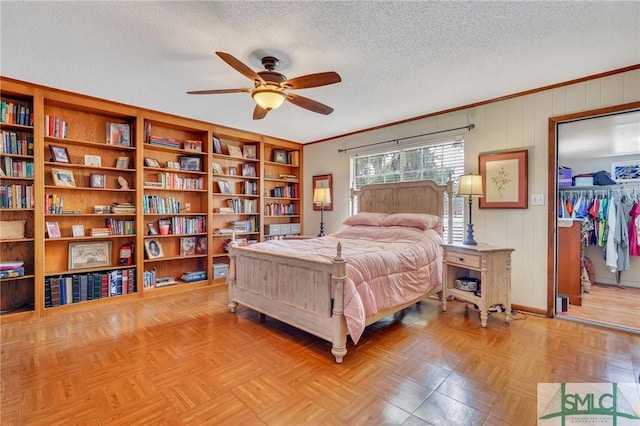 bedroom featuring light parquet floors, ceiling fan, a spacious closet, a textured ceiling, and a closet