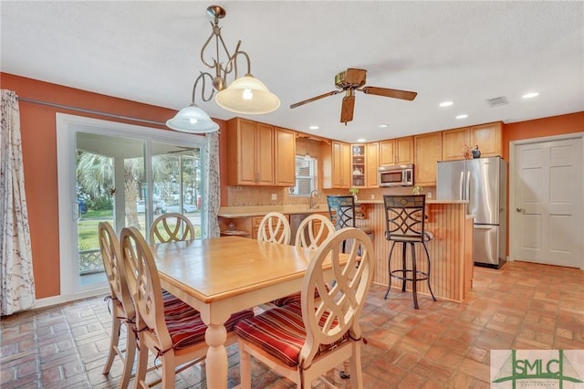 dining area with ceiling fan and sink