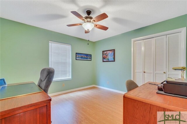 office area with ceiling fan, light wood-type flooring, and a textured ceiling