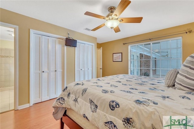 bedroom with multiple closets, ceiling fan, ensuite bathroom, and light wood-type flooring