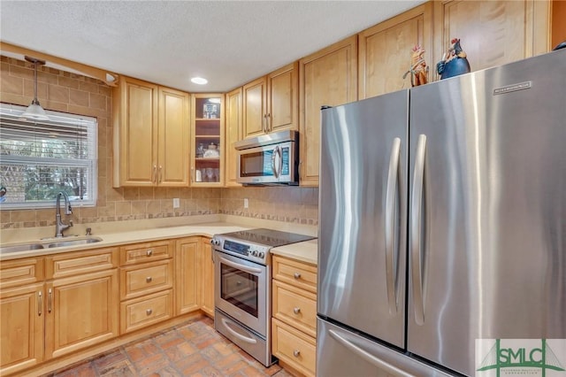 kitchen with sink, stainless steel appliances, tasteful backsplash, a textured ceiling, and light brown cabinetry