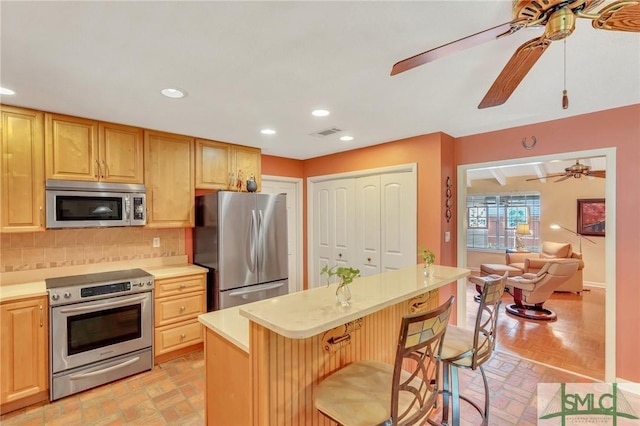 kitchen with appliances with stainless steel finishes, a center island, tasteful backsplash, and a breakfast bar area