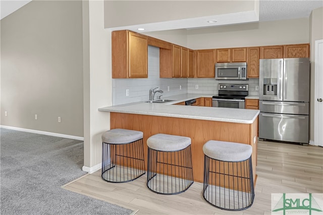 kitchen featuring sink, appliances with stainless steel finishes, tasteful backsplash, light carpet, and kitchen peninsula