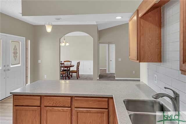 kitchen with sink, light hardwood / wood-style floors, a chandelier, and kitchen peninsula