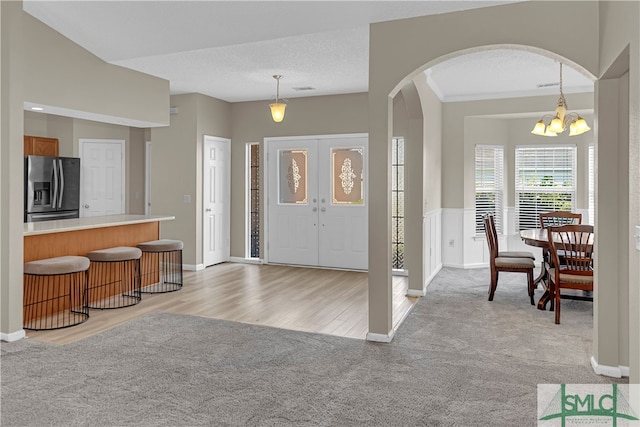 entryway featuring a textured ceiling, light hardwood / wood-style flooring, and a chandelier