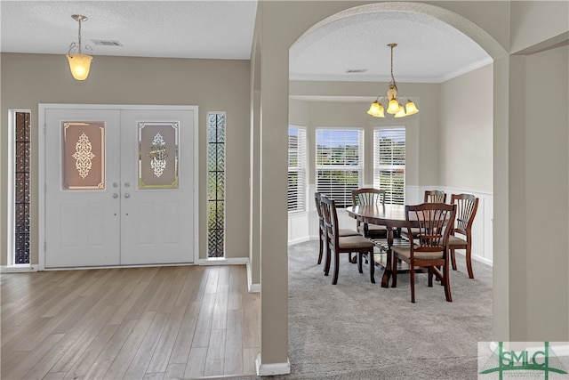 carpeted entrance foyer with a notable chandelier, a textured ceiling, french doors, and ornamental molding