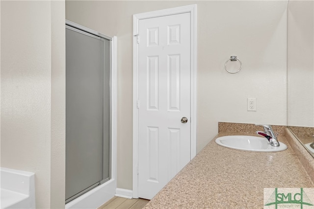 bathroom with a shower with door, hardwood / wood-style floors, and vanity