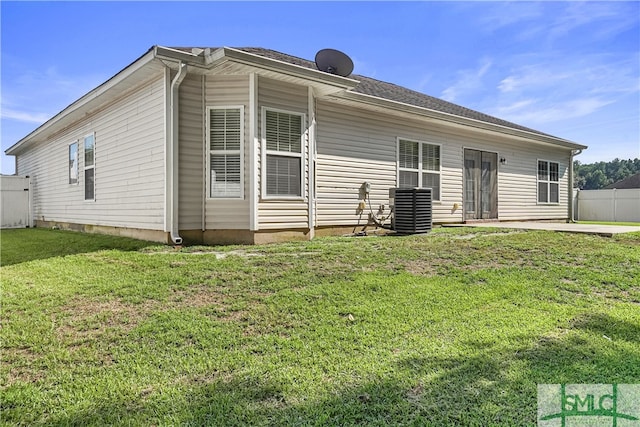 rear view of house with a patio area, a yard, and central AC