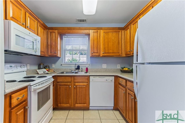 kitchen featuring brown cabinets, light countertops, visible vents, a sink, and white appliances