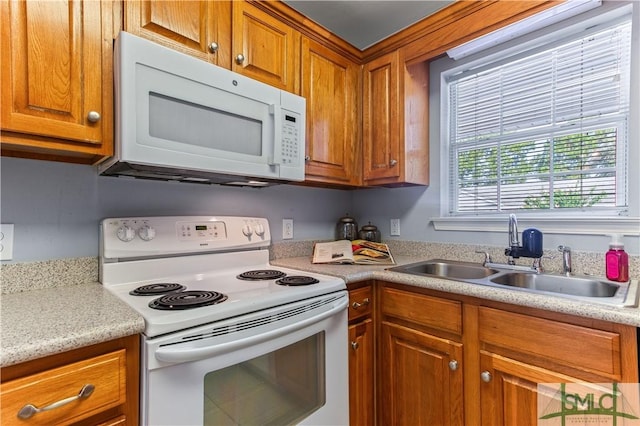 kitchen featuring light countertops, white appliances, a sink, and brown cabinets