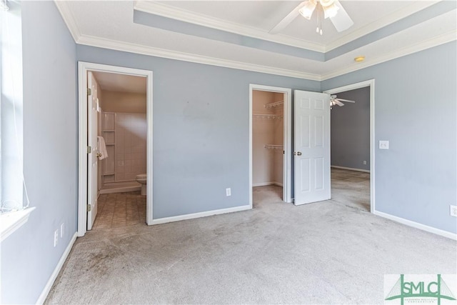 unfurnished bedroom with a walk in closet, a raised ceiling, light colored carpet, and crown molding