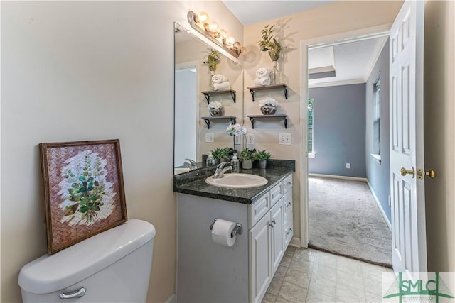 half bathroom with ornamental molding, baseboards, vanity, and toilet