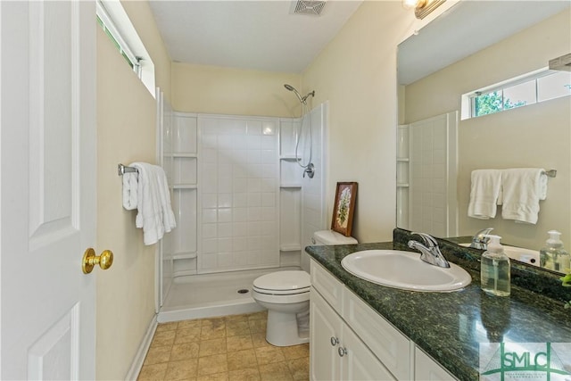 full bathroom with baseboards, visible vents, tiled shower, toilet, and vanity