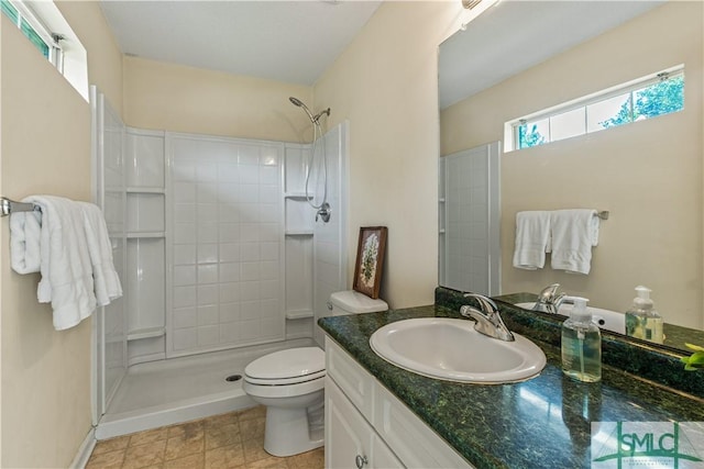 bathroom with tiled shower, vanity, and toilet