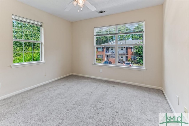 carpeted spare room featuring baseboards, a ceiling fan, visible vents, and a healthy amount of sunlight