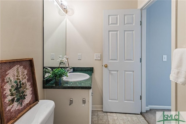 half bathroom featuring toilet, vanity, and baseboards