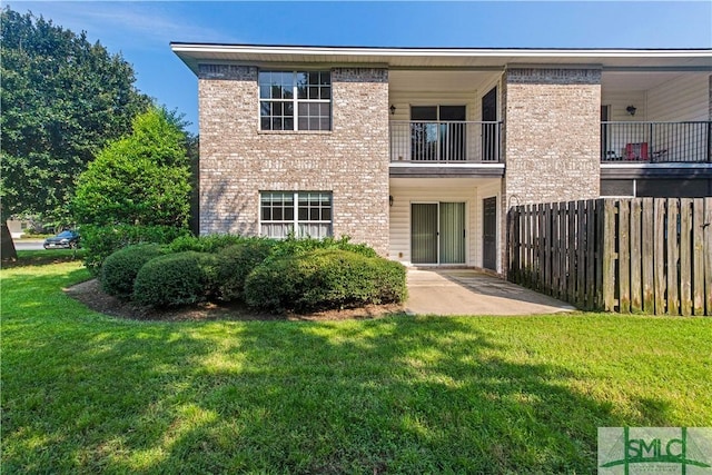 back of property featuring brick siding, a patio, and a lawn