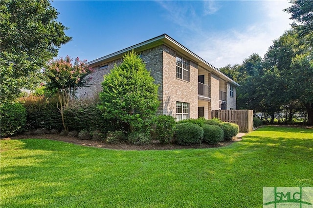 view of home's exterior with a yard, brick siding, and fence