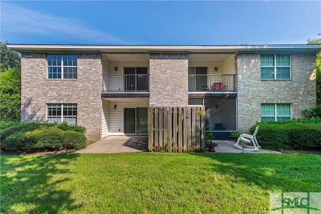 rear view of property featuring a patio, a yard, and brick siding