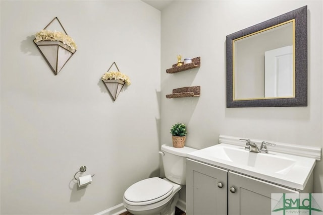 half bath featuring toilet, baseboards, and vanity