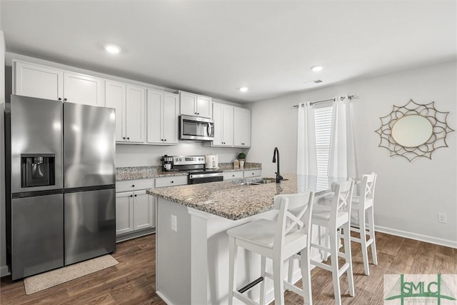 kitchen with a kitchen island with sink, appliances with stainless steel finishes, white cabinets, and a sink