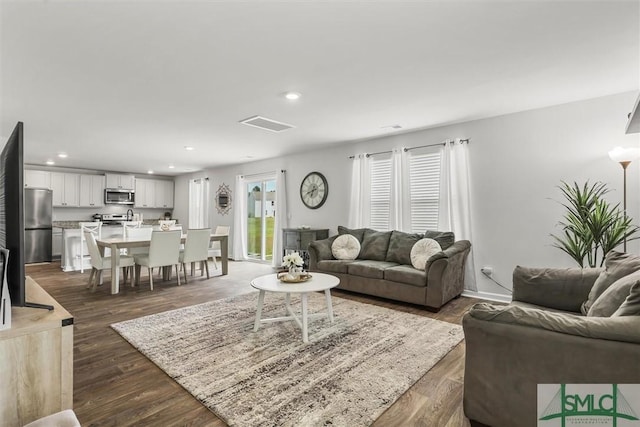 living room featuring recessed lighting, dark wood-style flooring, visible vents, and baseboards