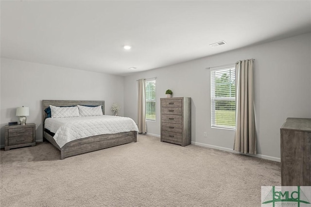 bedroom with baseboards, visible vents, and light colored carpet