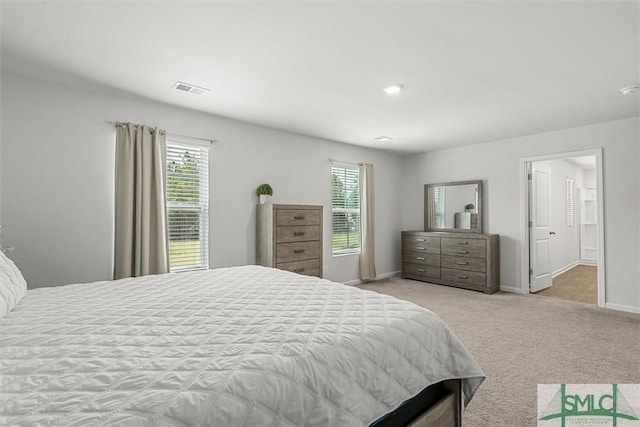 bedroom featuring light colored carpet, visible vents, baseboards, and multiple windows