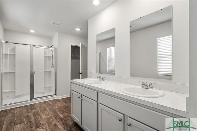 full bath featuring a stall shower, a sink, and wood finished floors