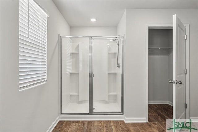 full bath featuring a shower stall, baseboards, and wood finished floors