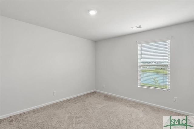 unfurnished room with baseboards, visible vents, and light colored carpet