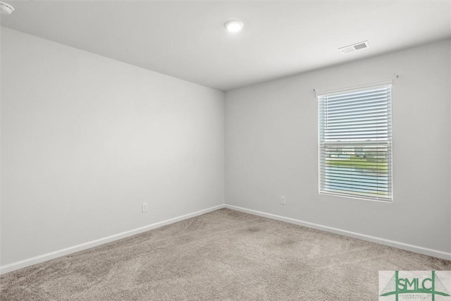 carpeted spare room with visible vents and baseboards