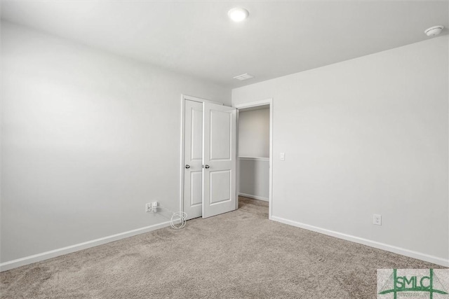 unfurnished bedroom featuring light carpet, baseboards, and a closet