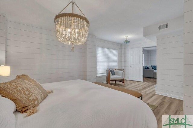 bedroom with light hardwood / wood-style flooring and a notable chandelier