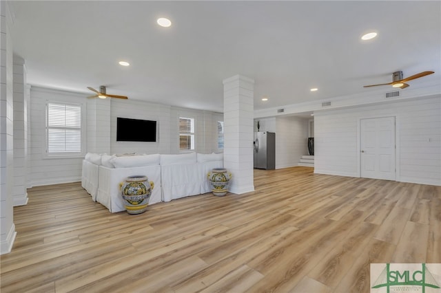 unfurnished living room with decorative columns, ceiling fan, and light hardwood / wood-style floors