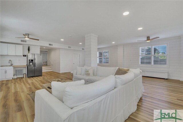 living room featuring ceiling fan, sink, and light wood-type flooring