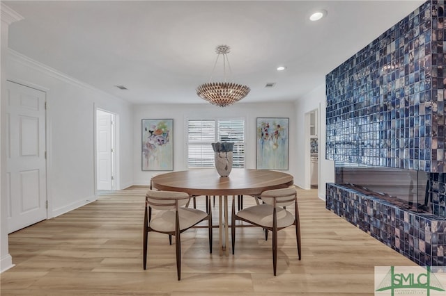 dining area with ornamental molding and light hardwood / wood-style floors