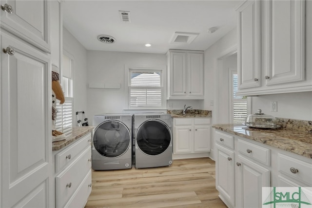 laundry area featuring light wood-type flooring, a healthy amount of sunlight, and washer and dryer