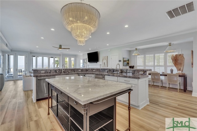 kitchen featuring light wood-type flooring, a kitchen island, ornamental molding, and stainless steel dishwasher