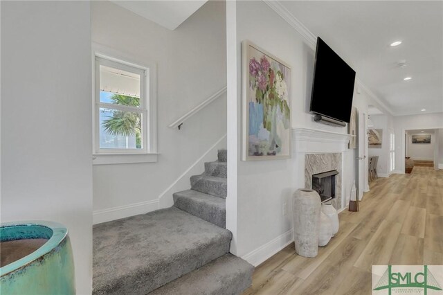 stairway featuring ornamental molding, a premium fireplace, and hardwood / wood-style flooring