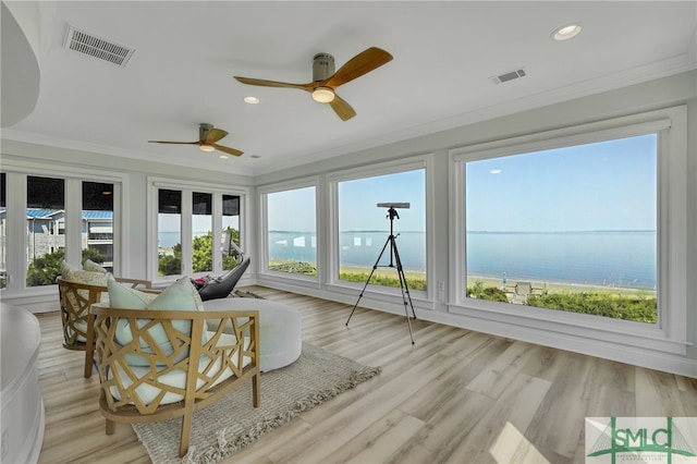 sunroom featuring ceiling fan and a water view