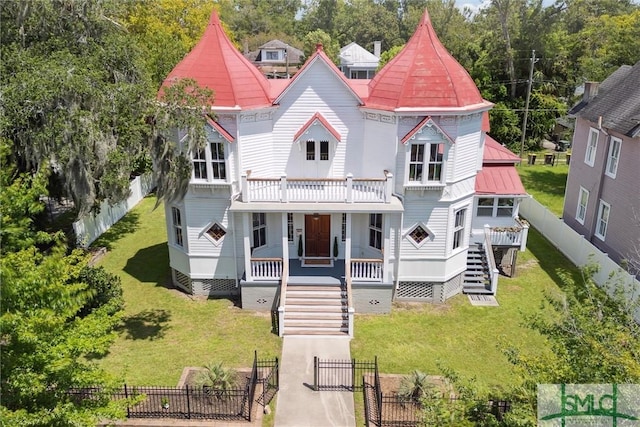 victorian home featuring a porch, a balcony, and a front yard